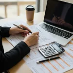 Freelancer calculating quarterly estimated taxes using annualized income method with financial documents and calculator